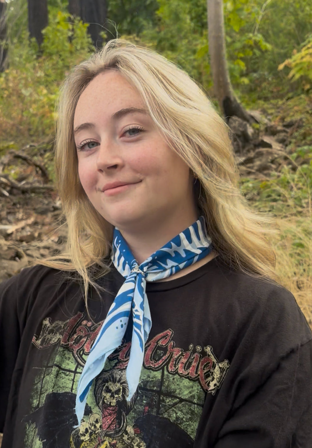 Person with a blue and white patterned scarf standing in a forest